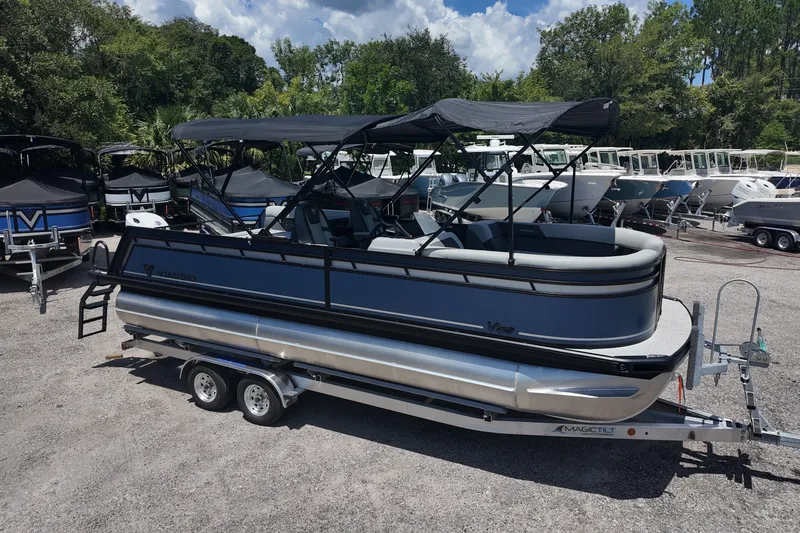 The Image of 2027 Viaggio x20u pontoon boat on trailer, parked outdoors with other boats. - 0
