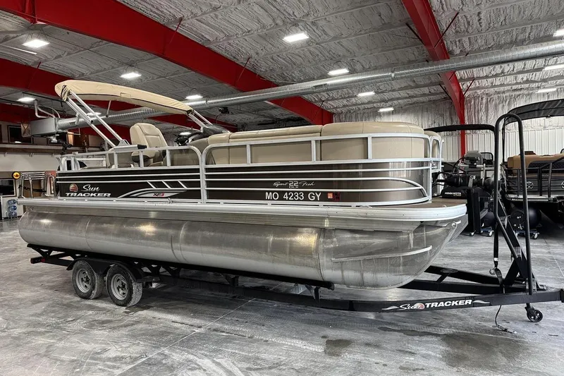 The Image of 2022 SUNTRACKER 22 XP3 FISH pontoon boat on trailer in indoor storage facility. - 1