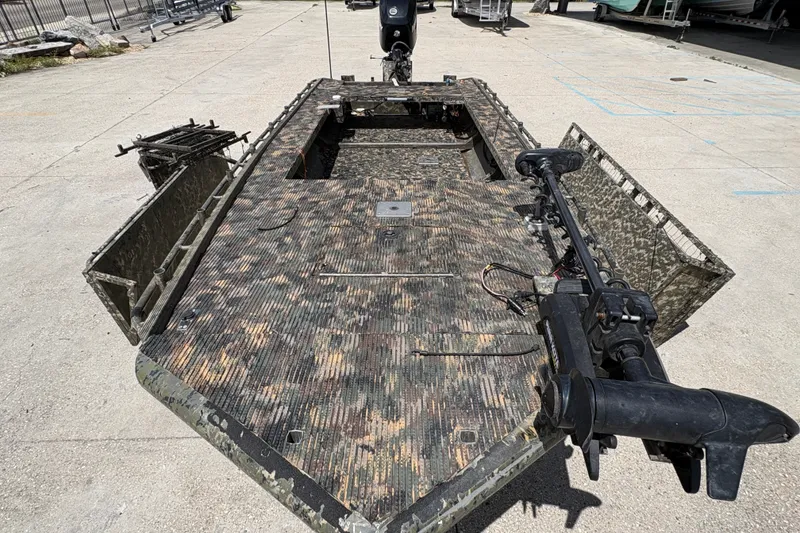 Slide: The Image of 2015 Gator Trax 16x44 boat with camouflage design and mounted motor, parked outdoors. - 15