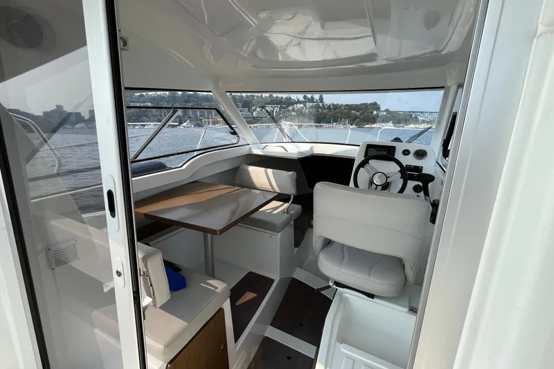 Slide: The Image of Interior of 2023 Beneteau Antares 7 boat, featuring helm and seating area with water view. - 17