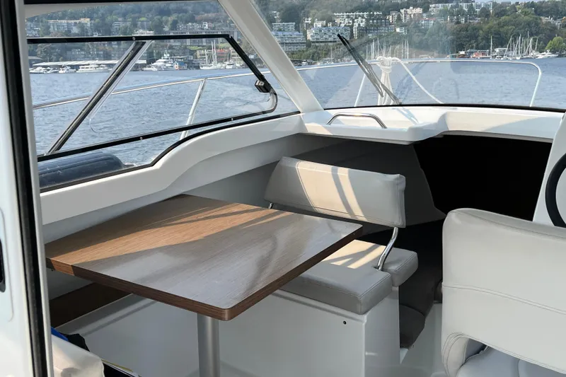Slide: The Image of Interior of 2023 Beneteau Antares 7 boat with seating and table, overlooking marina. - 16