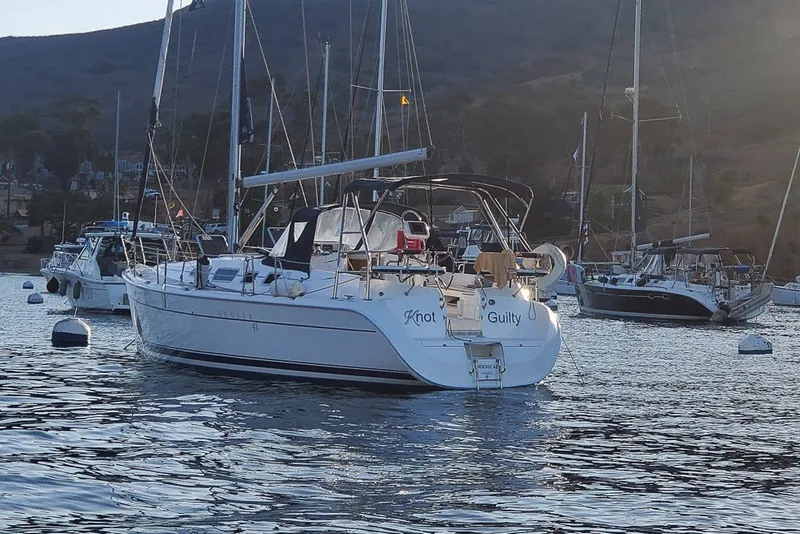 Slide: The Image of Sailboat "Knot Guilty," a 2007 Hunter 41 Aft Cockpit, anchored in a scenic harbor. - 1