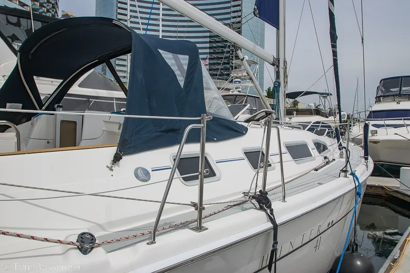 Slide: The Image of 2007 Hunter 41 Aft Cockpit sailboat docked in marina, featuring sleek design and blue canopy. - 6