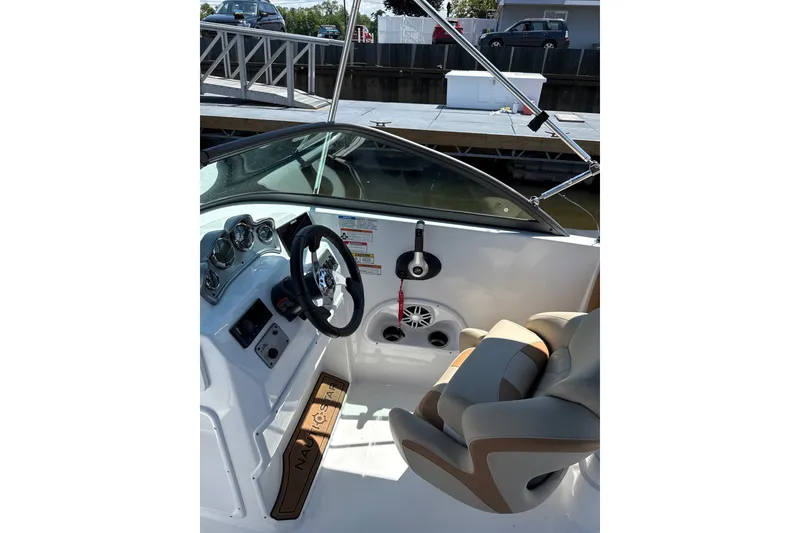 Slide: The Image of 2025 NauticStar 223 DC Deck boat interior with steering wheel and comfortable seating. - 5