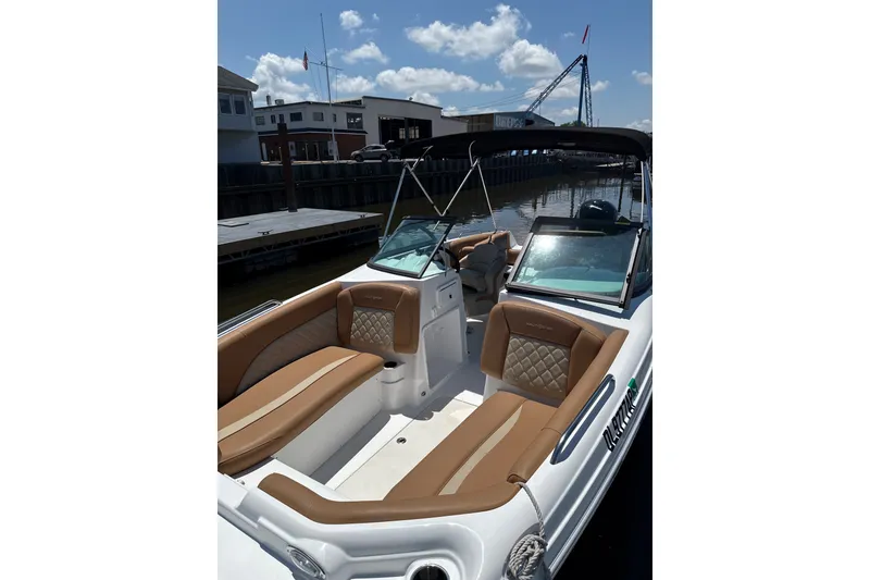 Slide: The Image of 2025 NauticStar 223 DC Deck boat with luxurious seating, docked under a sunny sky. - 2