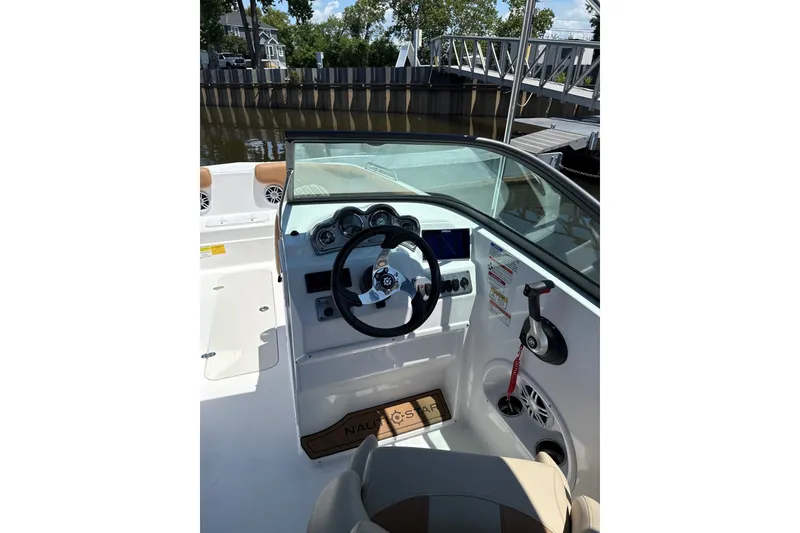 Slide: The Image of 2025 NauticStar 223 DC Deck boat interior with steering wheel and dashboard controls. - 6