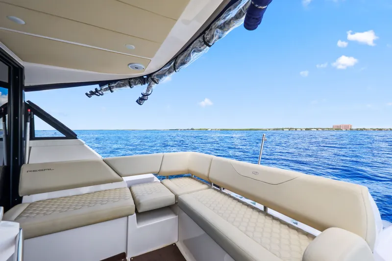 Slide: The Image of 2021 Regal 38 XO yacht interior with luxurious seating, overlooking serene blue waters. - 17