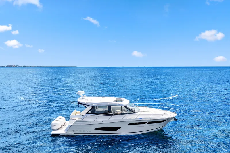 The Image of 2021 Regal 38 XO yacht cruising on clear blue ocean under a bright sky. - 1