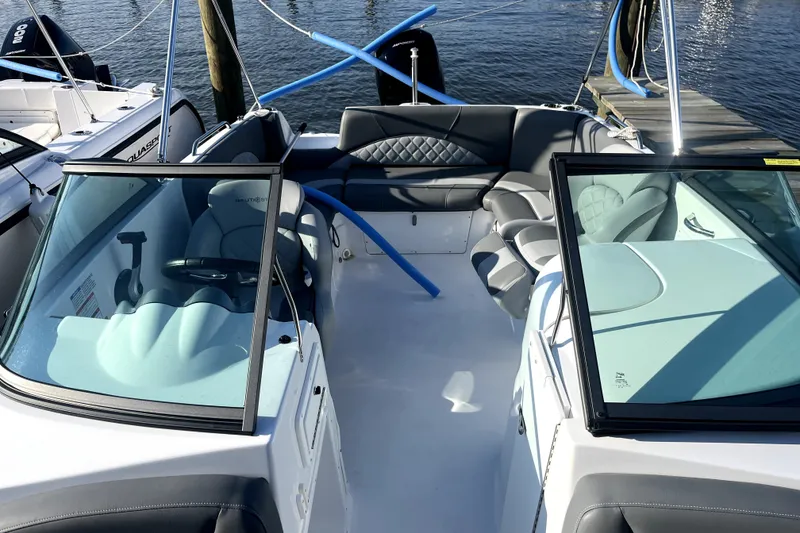 Slide: The Image of 2025 NauticStar 223 DC Deck boat interior with seating and steering wheel at dock. - 3
