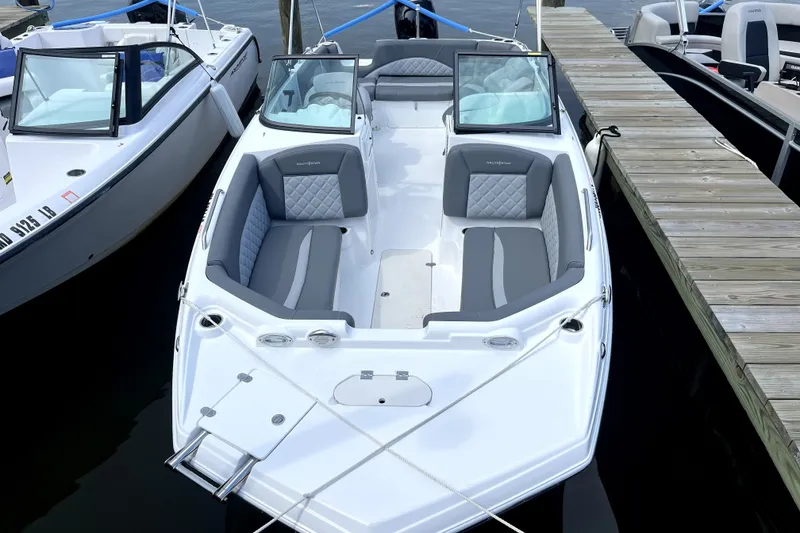 Slide: The Image of 2025 NauticStar 223 DC Deck boat docked, featuring sleek design and comfortable seating. - 2