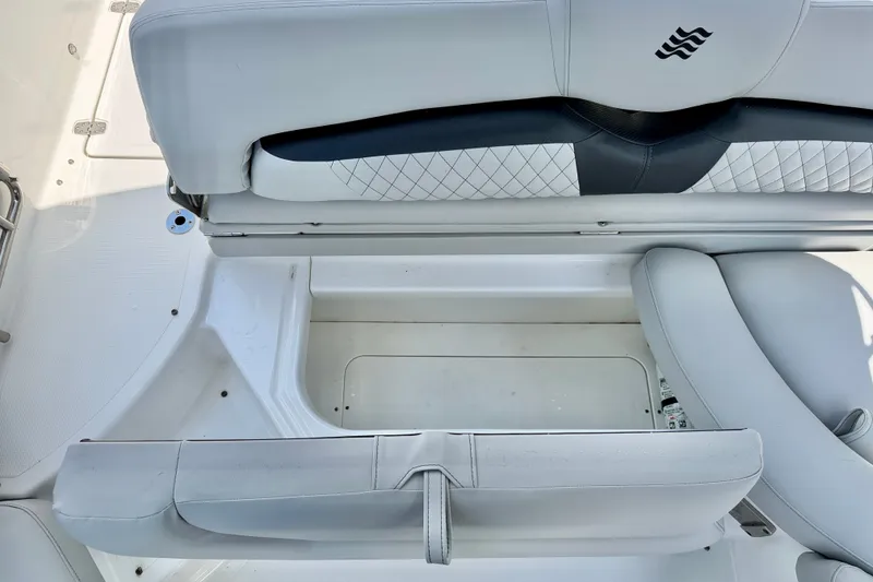 Slide: The Image of 2023 Four Winns HD8 OB boat interior with white cushioned seating and storage area. - 28