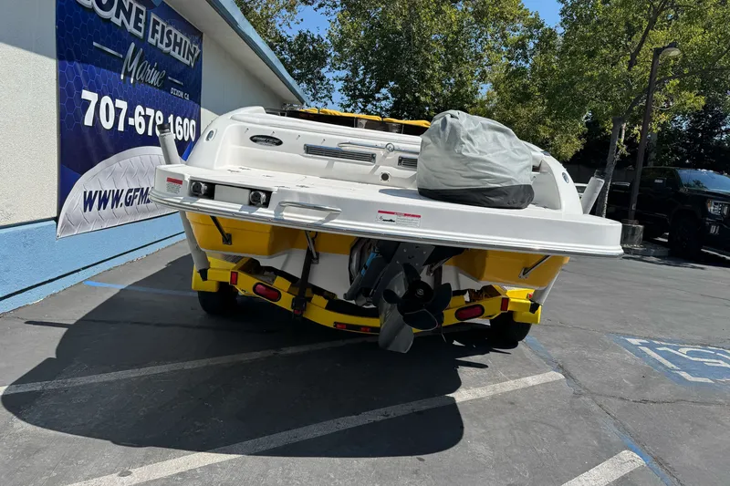Slide: The Image of 2006 Ebbtide 2100 Bow Rider boat, rear view, parked outdoors near a marine shop. - 3