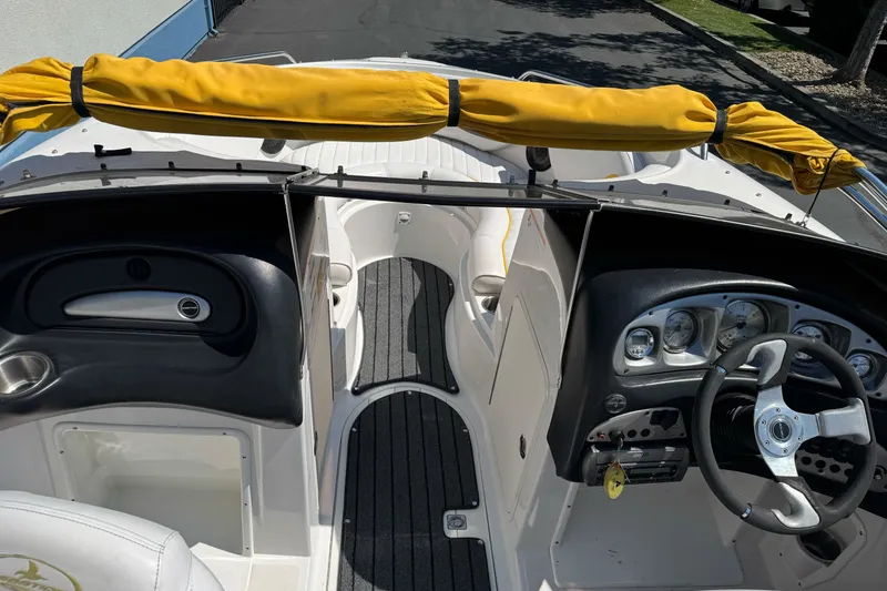 Slide: The Image of 2006 Ebbtide 2100 Bow Rider interior with steering wheel and dashboard, featuring yellow canopy. - 13