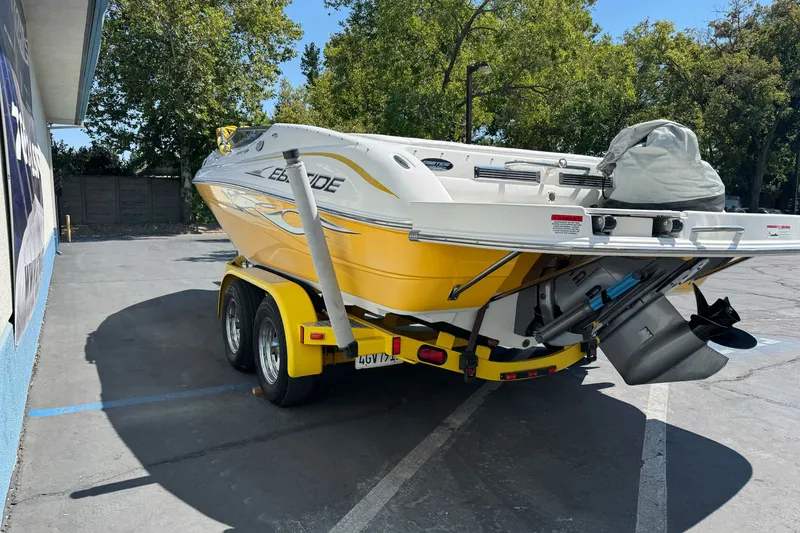 Slide: The Image of 2006 Ebbtide 2100 Bow Rider boat on trailer, parked outdoors, yellow and white design. - 4