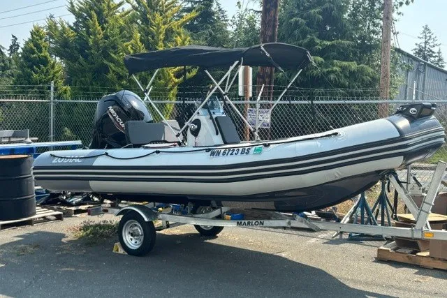 Slide: The Image of 2024 Zodiac Open 4.8 inflatable boat on trailer, parked outdoors. - 3