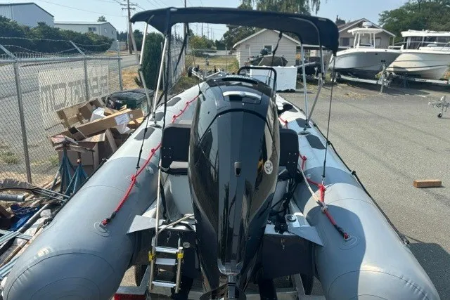 Slide: The Image of 2024 Zodiac Open 4.8 inflatable boat with outboard motor, parked outdoors. - 2