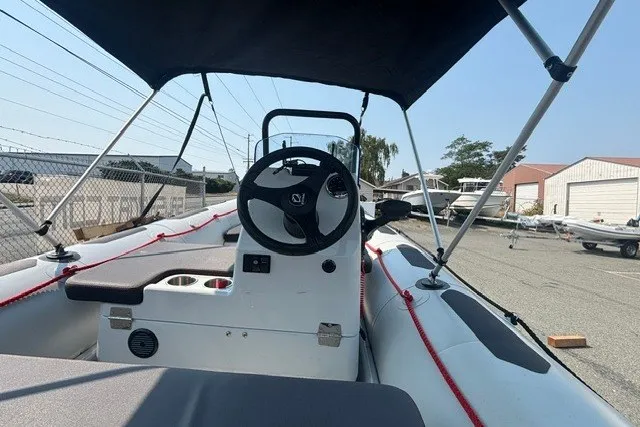 Slide: The Image of 2024 Zodiac Open 4.8 boat interior with steering wheel and canopy in a marina setting. - 5