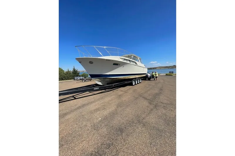 The Image of 1971 Chris-Craft 38 Commander boat on trailer by a lakeside under clear blue sky. - 0