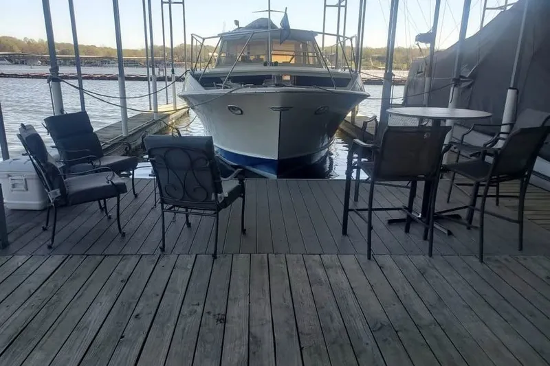 Slide: The Image of 1971 Chris-Craft 38 Commander docked, surrounded by patio chairs on a wooden deck. - 6