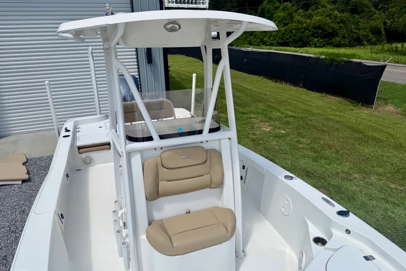 Slide: The Image of 2017 Sea Hunt BX25BR boat with beige seating, docked near a grassy area. - 7