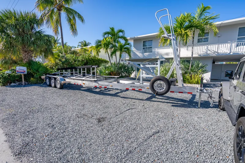 Slide: The Image of Trailer for Freeman 35 boat, 2026 model, parked on gravel with tropical plants. - 19