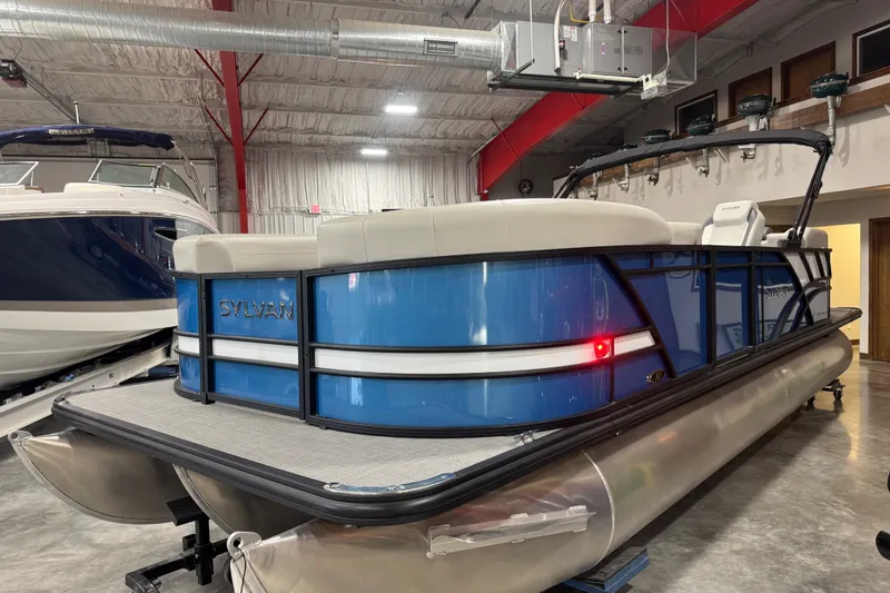 Slide: The Image of 2026 Sylvan X5 CLZ pontoon boat in showroom, featuring sleek blue design and modern amenities. - 2