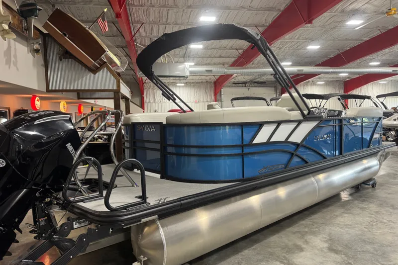 Slide: The Image of 2026 Sylvan X5 CLZ pontoon boat in showroom, featuring sleek blue design and powerful engine. - 6