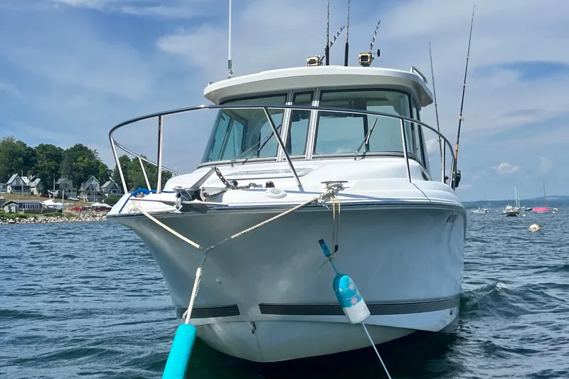 Slide: The Image of 2005 Wellcraft 252 Coastal boat anchored on calm water with fishing rods visible. - 9