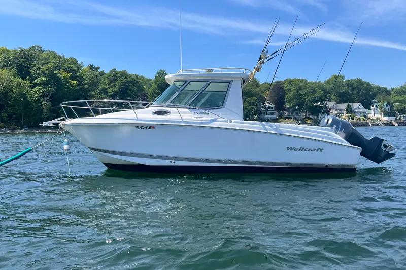 The Image of 2005 Wellcraft 252 Coastal boat on water with fishing rods, surrounded by trees and houses. - 1