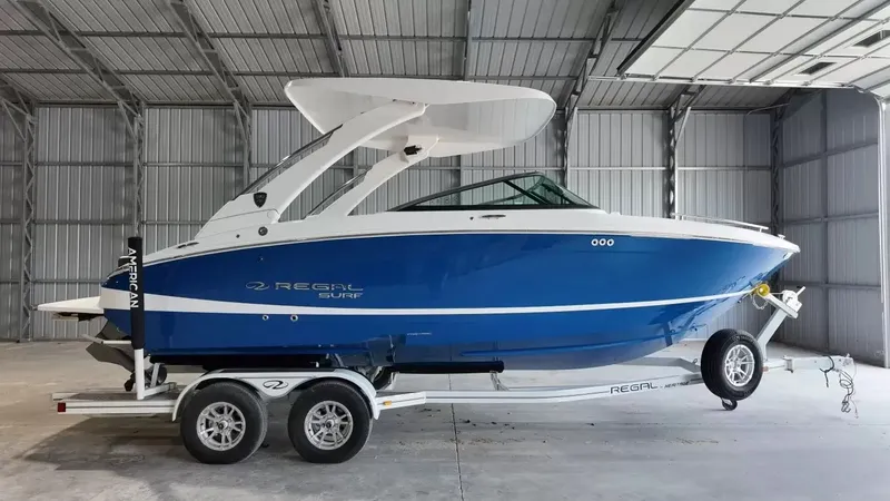 The Image of A 2027 Regal LS4 Surf boat on a trailer inside a warehouse. - 1