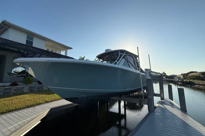 Slide: The Image of 2017 Sailfish 325 DC boat docked near a modern waterfront home. - 2