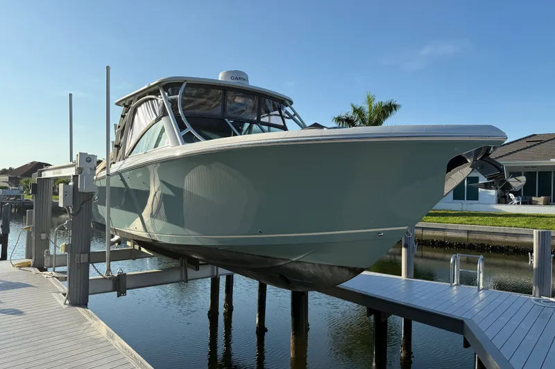 The Image of 2017 Sailfish 325 DC boat on lift at dockside, clear sky background. - 1