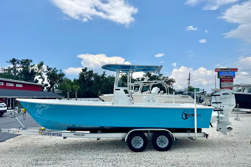 The Image of 2027 C-Hawk 25 Center Console boat on trailer, blue hull, outdoor dealership setting. - 0