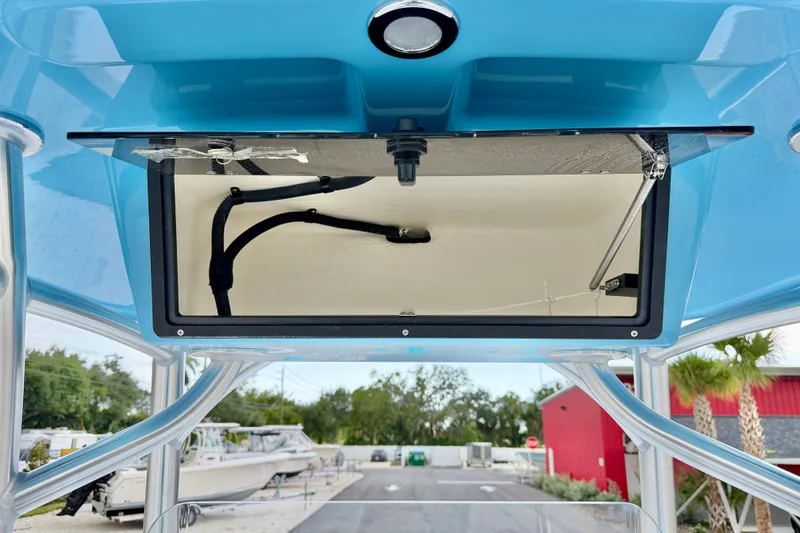 Slide: The Image of 2027 C-Hawk 25 Center Console boat with open storage compartment, blue canopy, and visible wiring. - 24