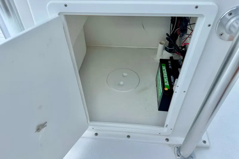 Slide: The Image of Open storage compartment in 2027 C-Hawk 25 Center Console boat, featuring an Interstate battery. - 15