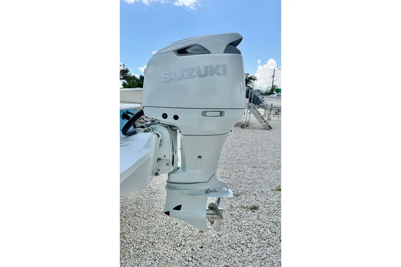 Slide: The Image of Suzuki outboard motor on a 2027 C-Hawk 25 Center Console boat, parked on gravel. - 35