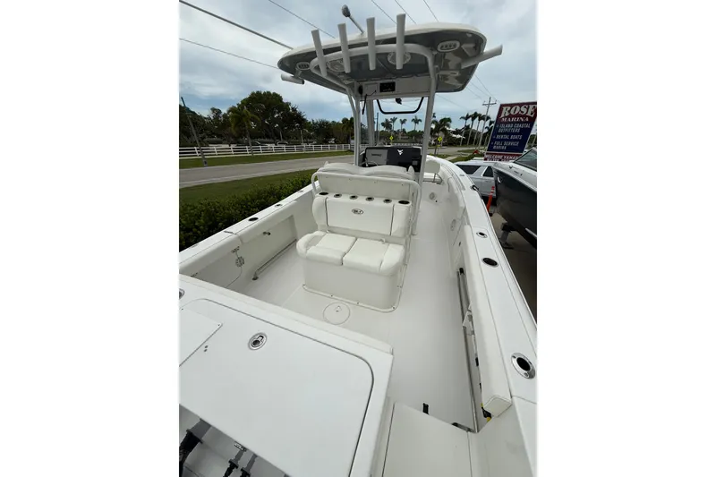 Slide: The Image of 2018 Sea Hunt Gamefish 27 boat interior with seating and console, parked near a marina. - 11