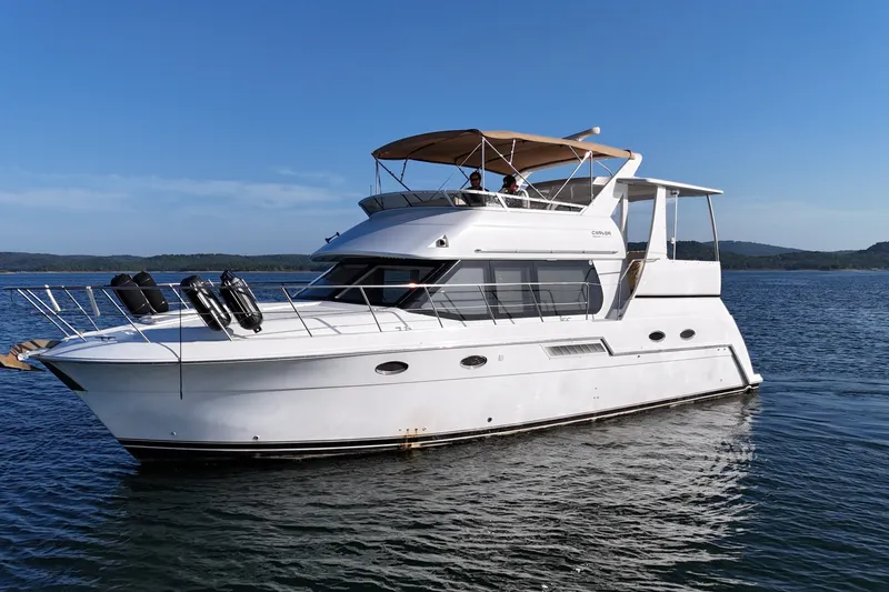 The Image of 2000 Carver 406 Aft Cabin Motor Yacht cruising on a serene lake under clear skies. - 0