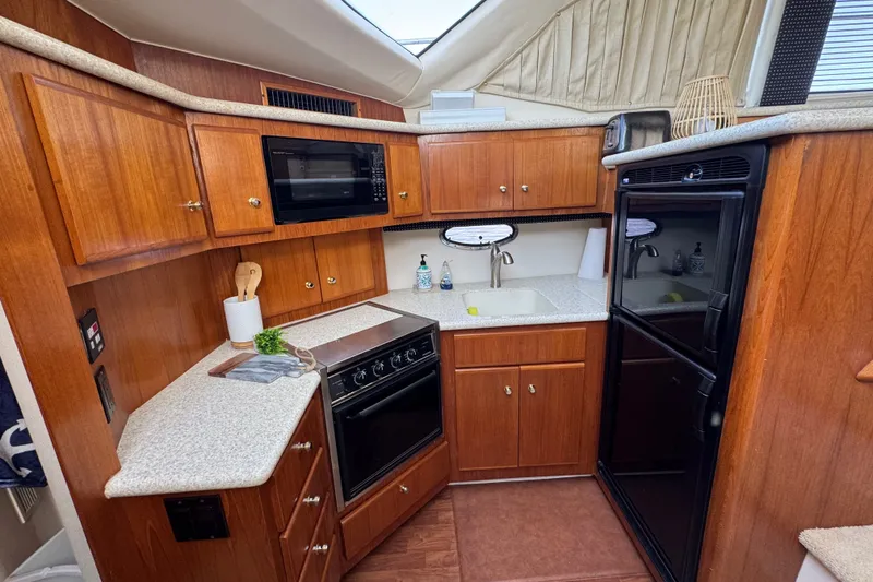 Slide: The Image of Interior of 2000 Carver 406 Aft Cabin Motor Yacht kitchen with wood cabinetry and appliances. - 24
