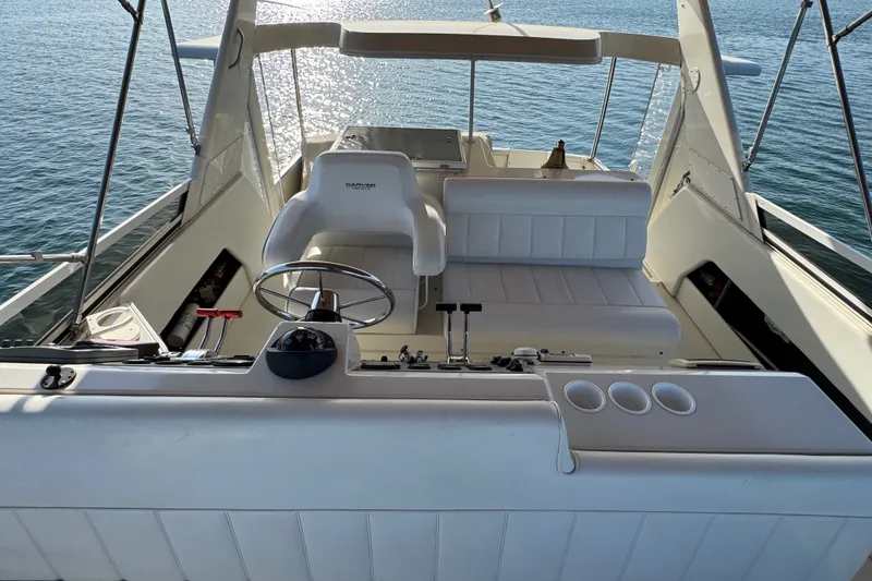 Slide: The Image of 2000 Carver 406 Aft Cabin Motor Yacht helm with white seating and ocean view. - 13