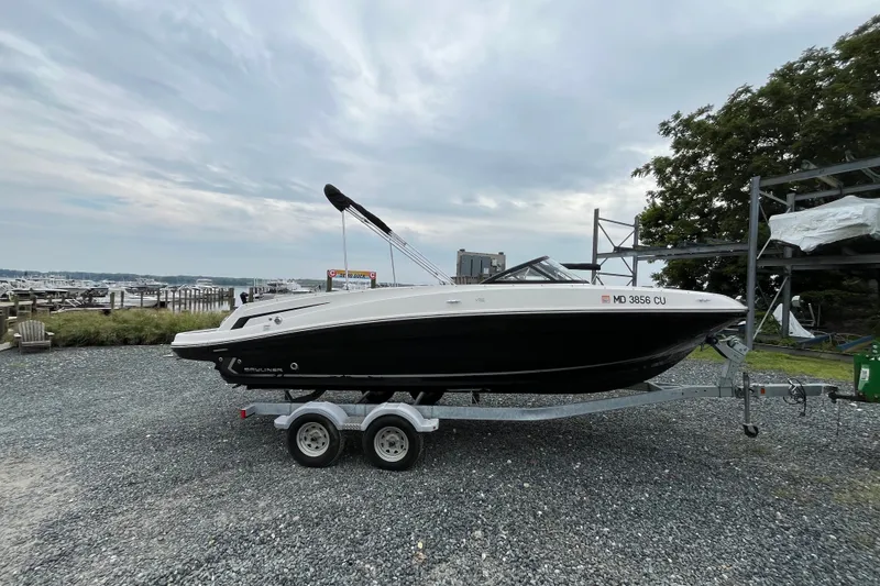 The Image of 2023 Bayliner VR6 Bowrider I/O on trailer at marina, cloudy sky background. - 0