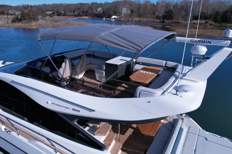 Slide: The Image of 2024 Fairline Phantom 65 yacht with spacious deck and canopy on serene water. - 7