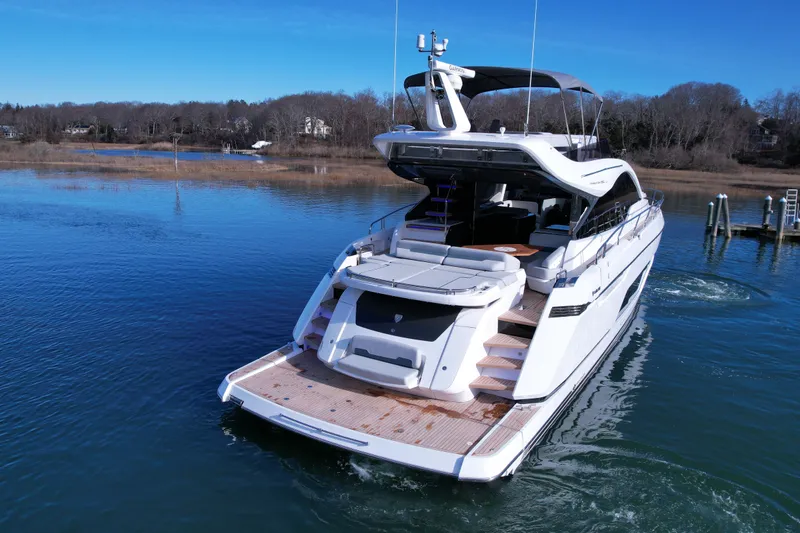 Slide: The Image of 2024 Fairline Phantom 65 yacht on serene water, showcasing luxury design and spacious deck. - 5
