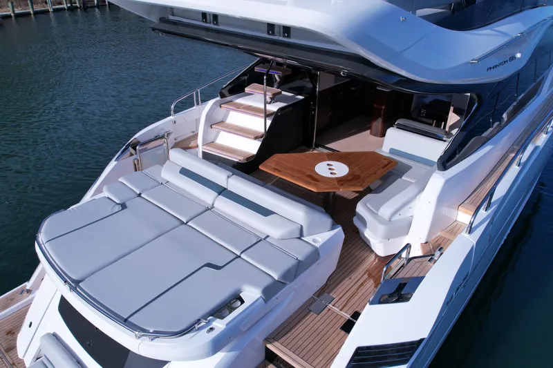 Slide: The Image of 2024 Fairline Phantom 65 yacht with luxurious deck seating and elegant wooden table. - 6