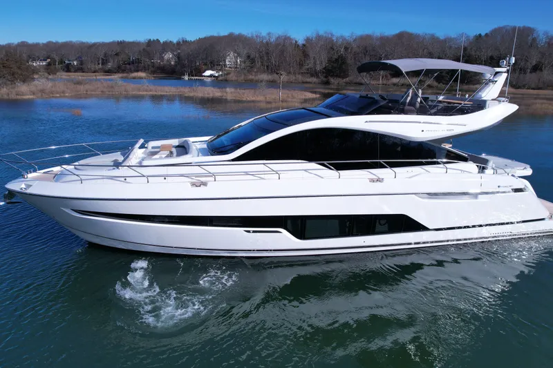 The Image of 2024 Fairline Phantom 65 yacht cruising on a serene lake under a clear blue sky. - 0