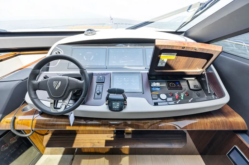 Slide: The Image of 2024 Fairline Phantom 65 yacht helm with modern controls and sleek wood finish. - 21
