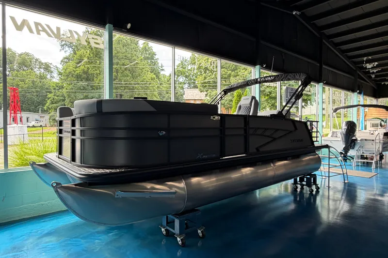 The Image of 2027 Sylvan X1 ULZ pontoon boat displayed in a showroom with large windows. - 0