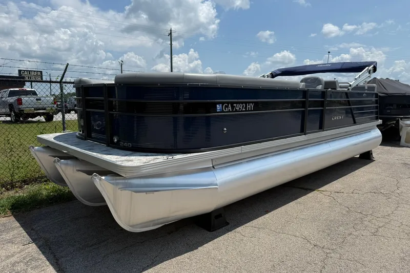 Slide: The Image of 2022 Crest 240 Classic CPTD pontoon boat parked outdoors under a cloudy sky. - 2