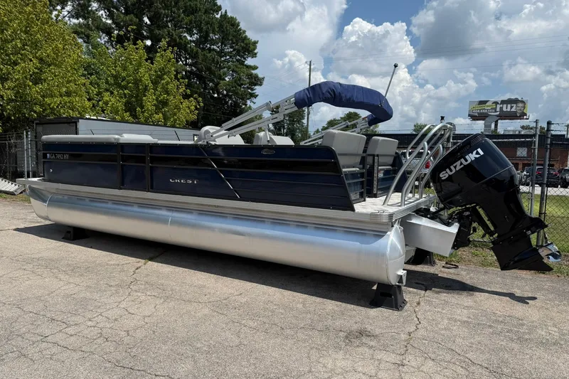 The Image of 2022 Crest 240 Classic CPTD pontoon boat with Suzuki outboard motor, parked outdoors. - 0
