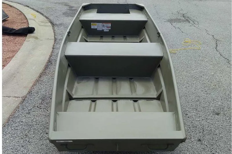 The Image of 2027 Tracker Grizzly 14 Jon boat on pavement, showcasing interior seating and design. - 0
